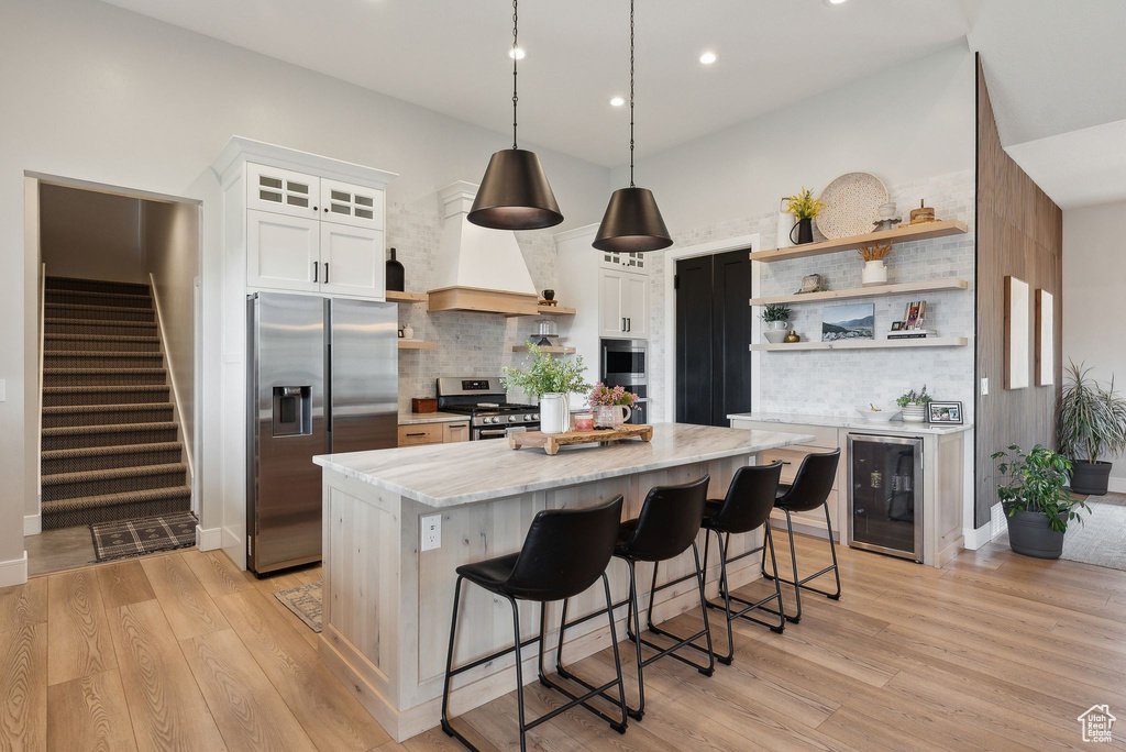 Kitchen with open shelves, wine cooler, a kitchen island, recessed lighting, and appliances with stainless steel finishes