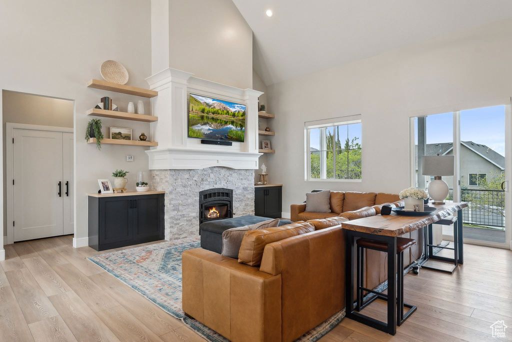 Living room featuring recessed lighting, high vaulted ceiling, light wood-style flooring, and a fireplace