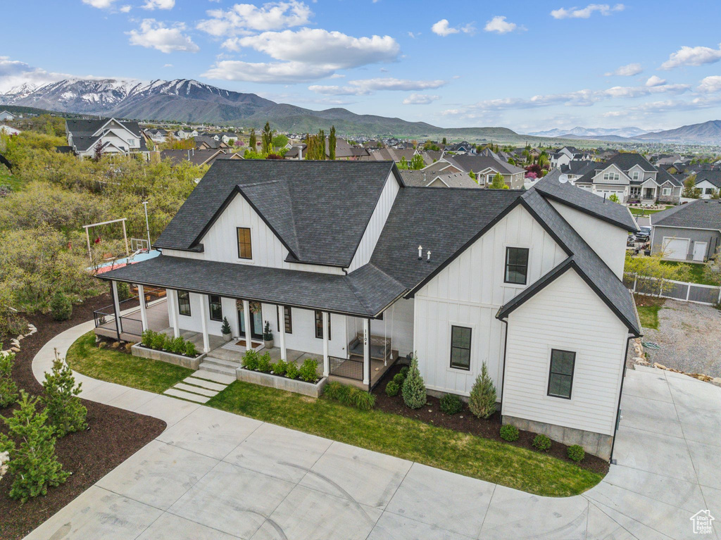 Modern farmhouse style home with a porch, board and batten siding, a mountain view, and roof with shingles