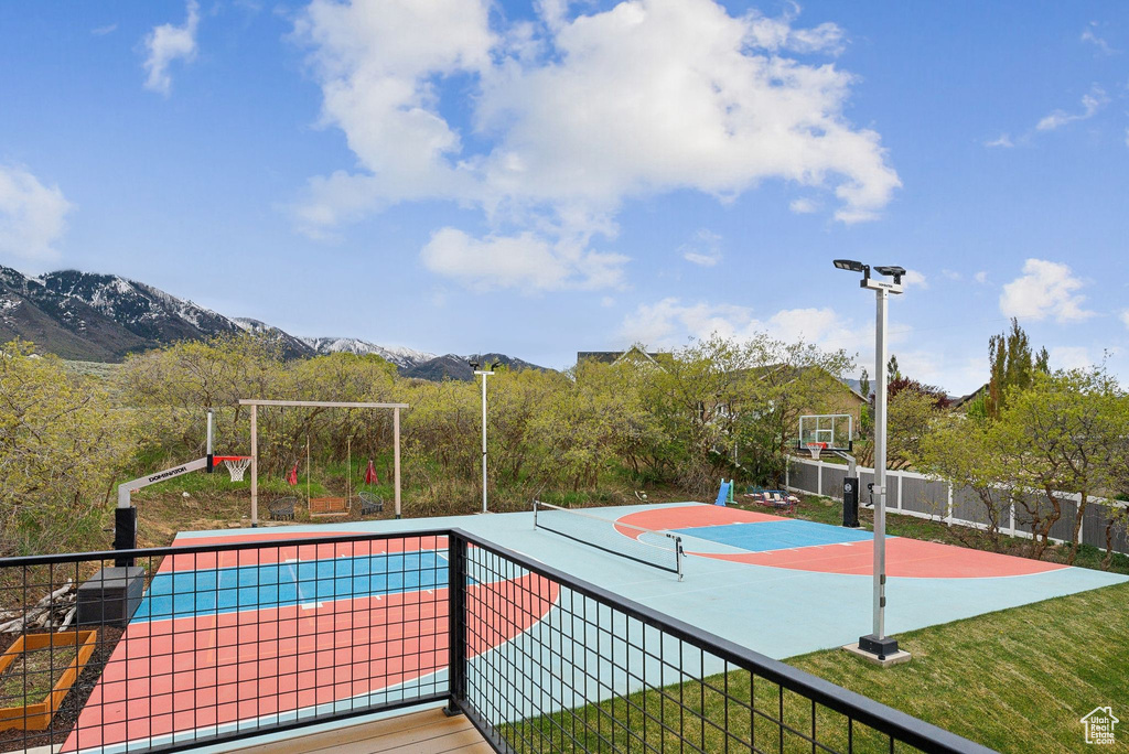 View of basketball court featuring a mountain view, fence, and basketball court