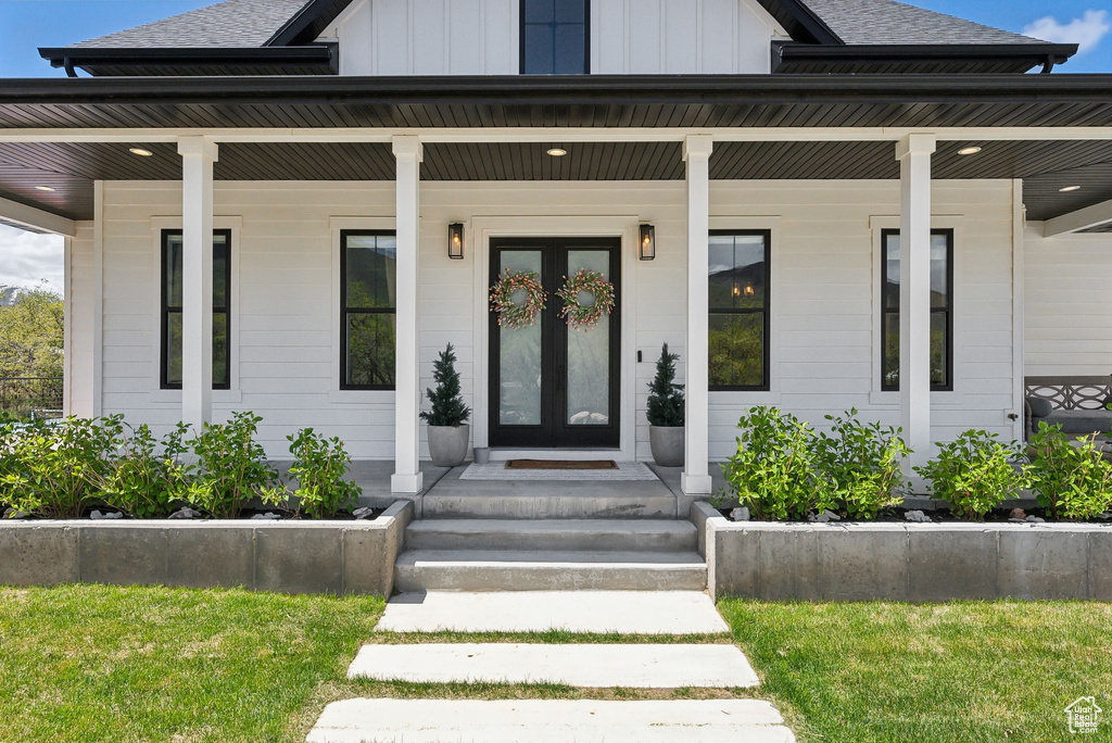 Entrance to property featuring a porch, a shingled roof, and board and batten siding