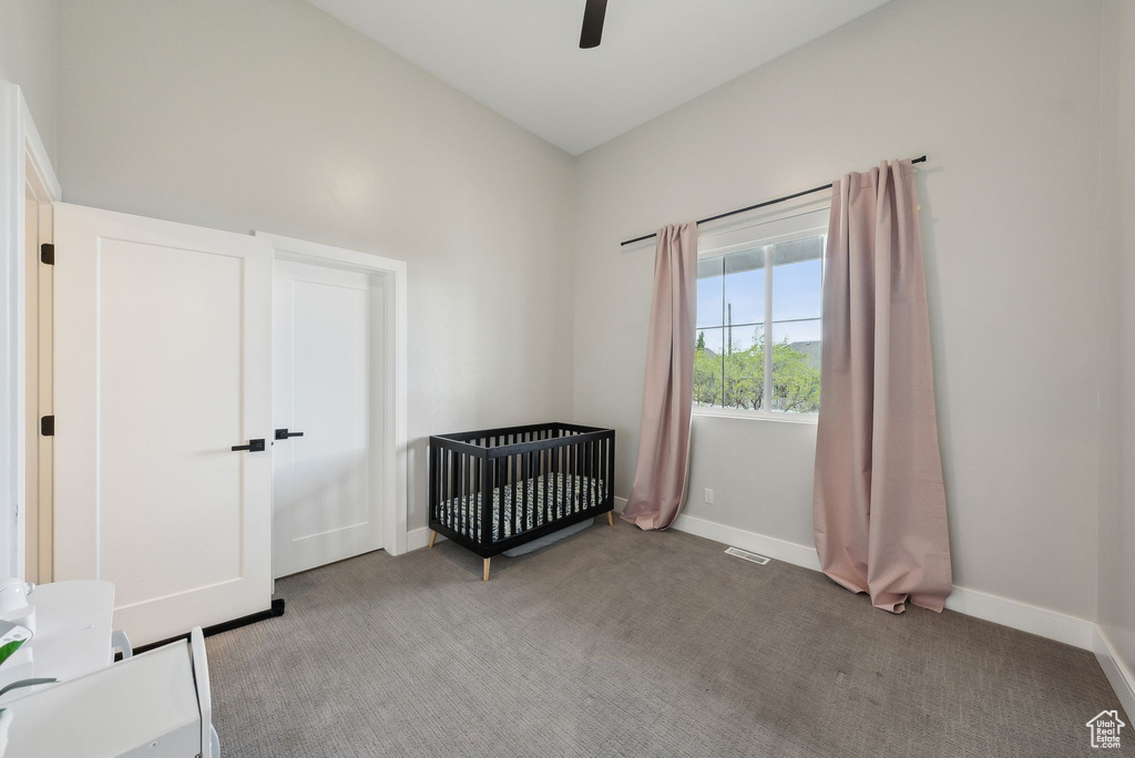 Unfurnished bedroom featuring a nursery area, ceiling fan, light carpet, baseboards, and visible vents