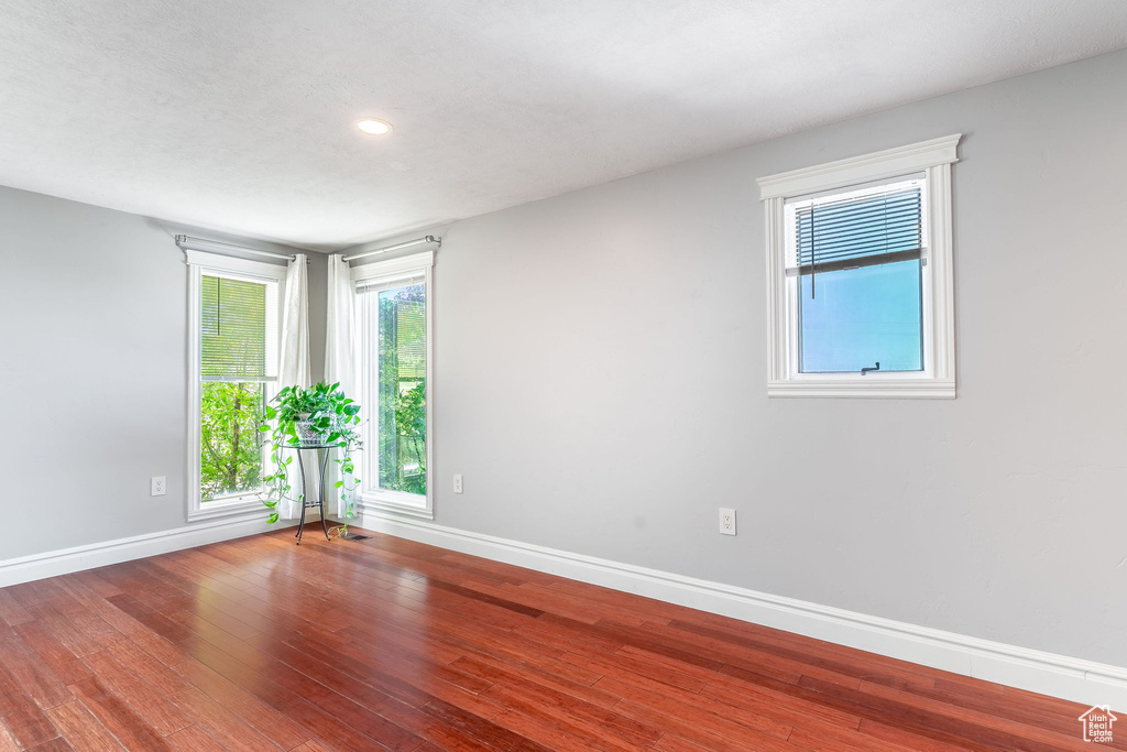 Spare room featuring baseboards, recessed lighting, plenty of natural light, and wood finished floors
