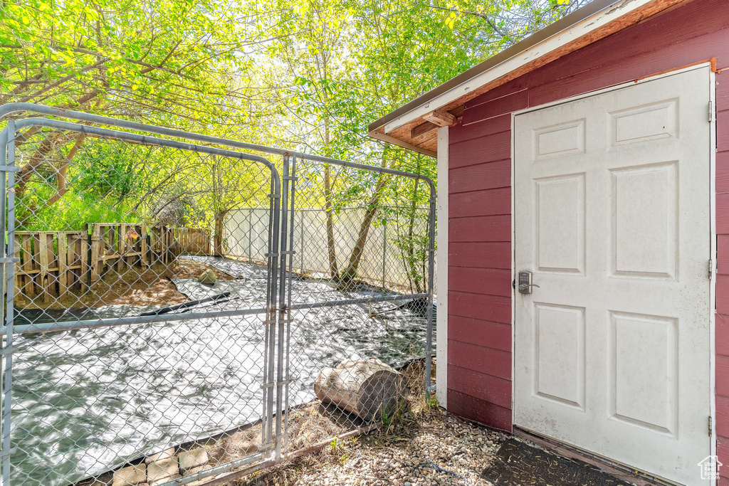 View of outdoor structure featuring a gate, fence, and an outbuilding