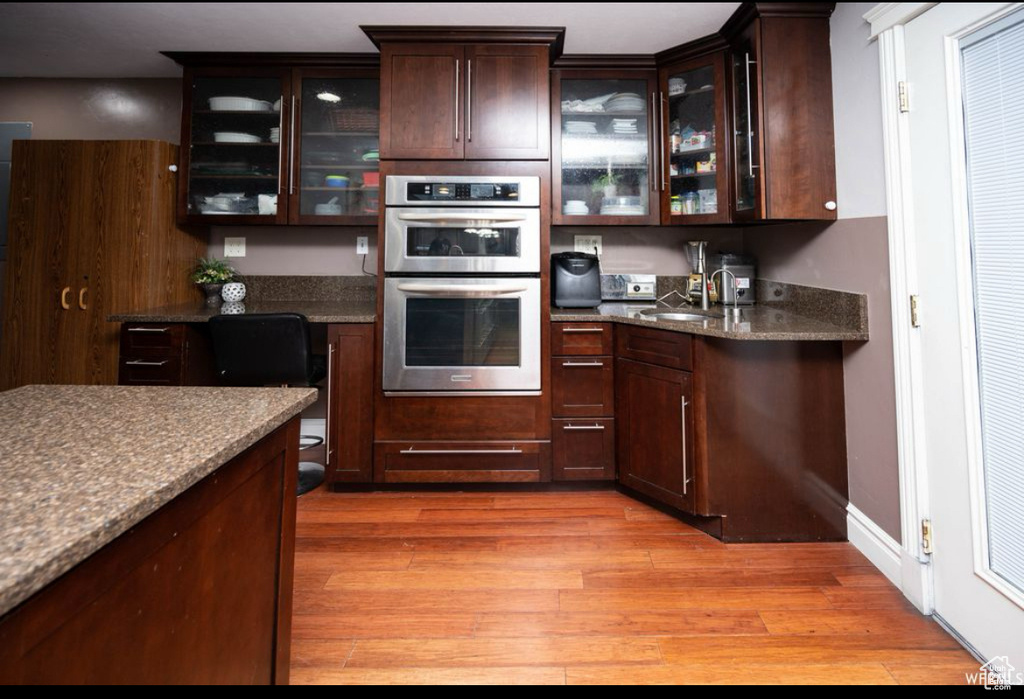 Kitchen featuring glass insert cabinets, double oven, and dark brown cabinets