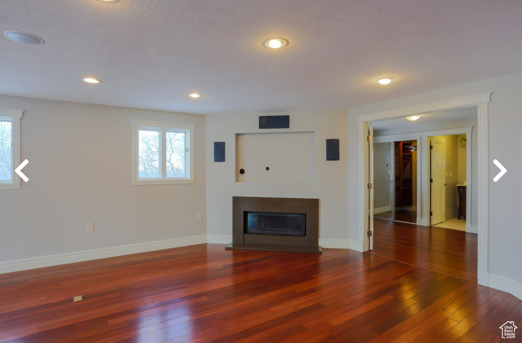 Unfurnished living room featuring a glass covered fireplace, wood-type flooring, and a healthy amount of sunlight