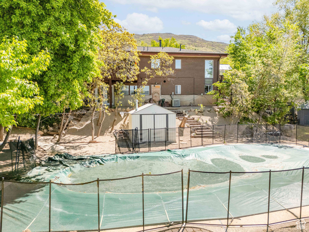 View of pool with an outbuilding, a fenced in pool, a mountain view, fence, and a shed