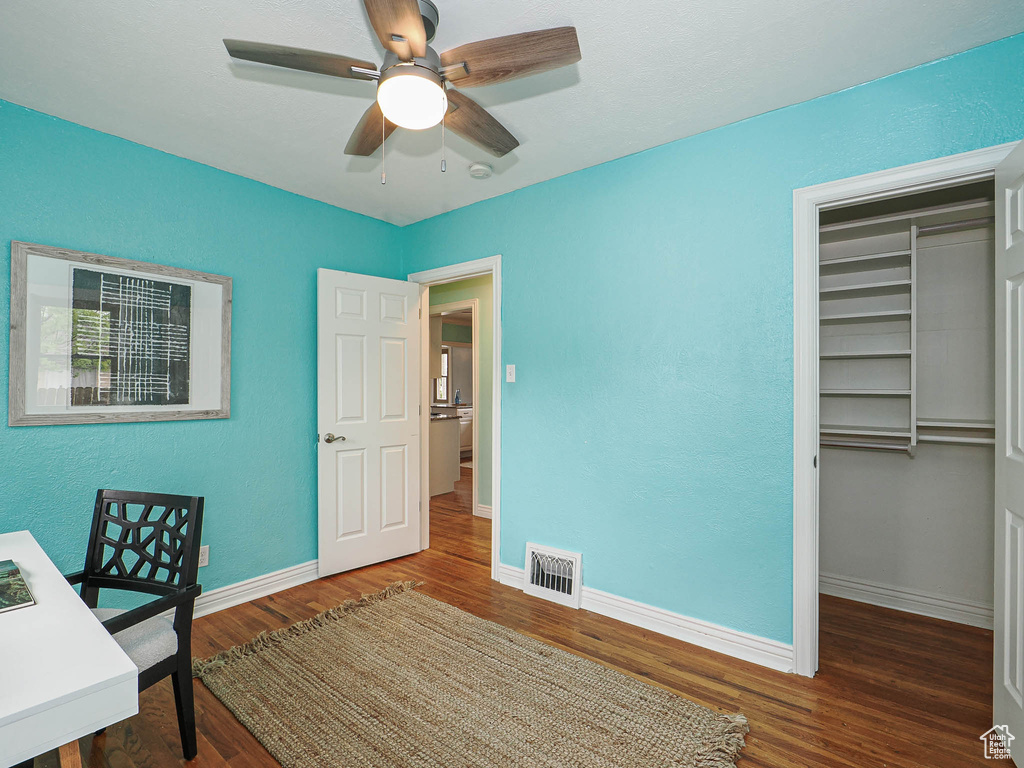 Unfurnished office with visible vents, a ceiling fan, baseboards, and wood finished floors