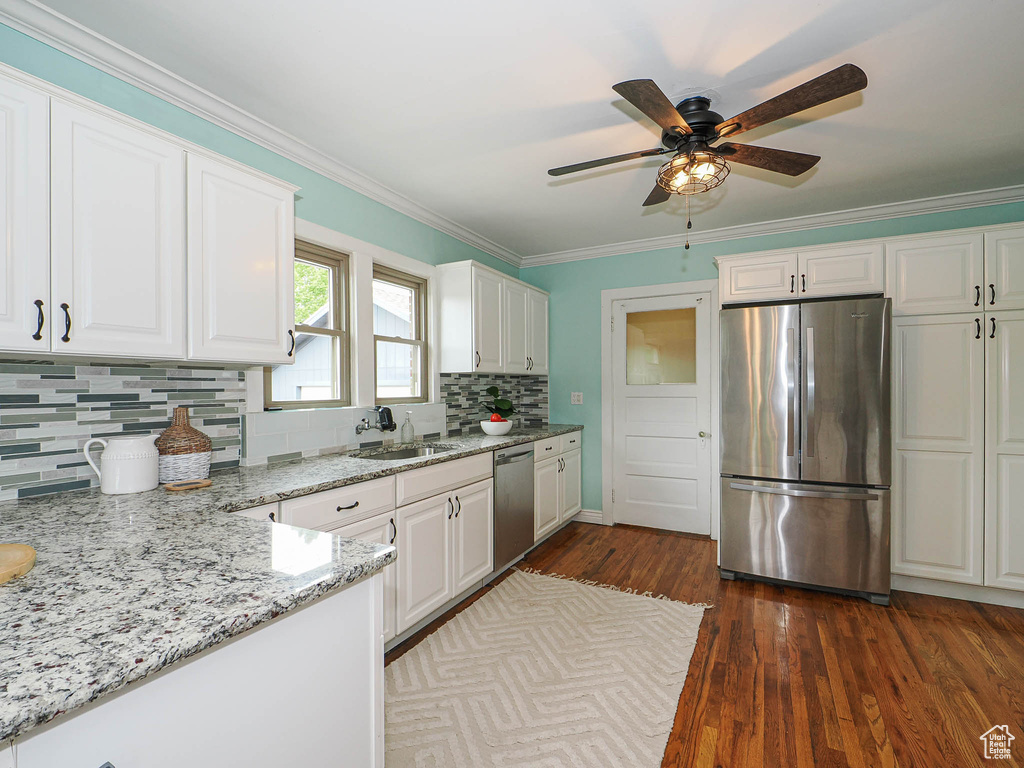 Kitchen with a sink, appliances with stainless steel finishes, white cabinets, and decorative backsplash