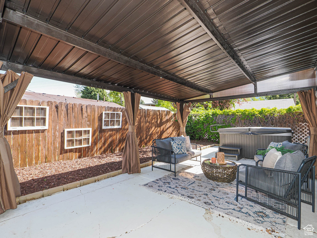 View of patio with a hot tub, a fenced backyard, and an outdoor hangout area