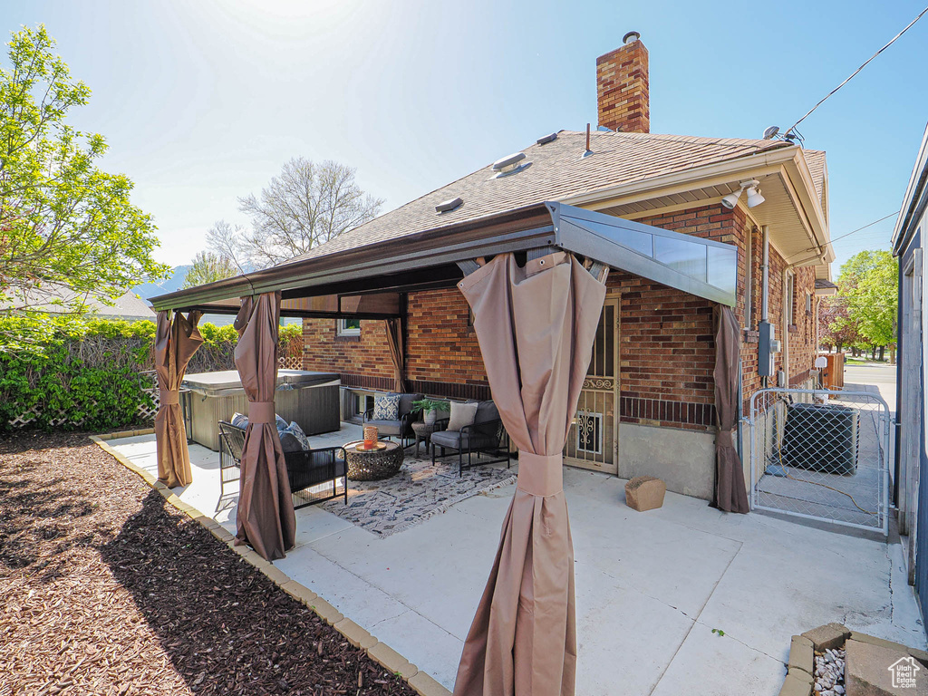 View of patio featuring an outdoor hangout area, fence, and a hot tub