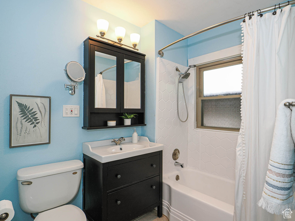 Bathroom with vanity, toilet, and shower / tub combo with curtain