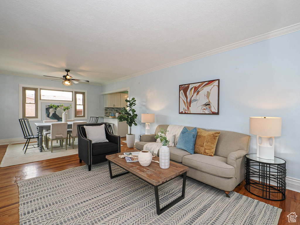 Living area with crown molding, a ceiling fan, baseboards, and wood finished floors
