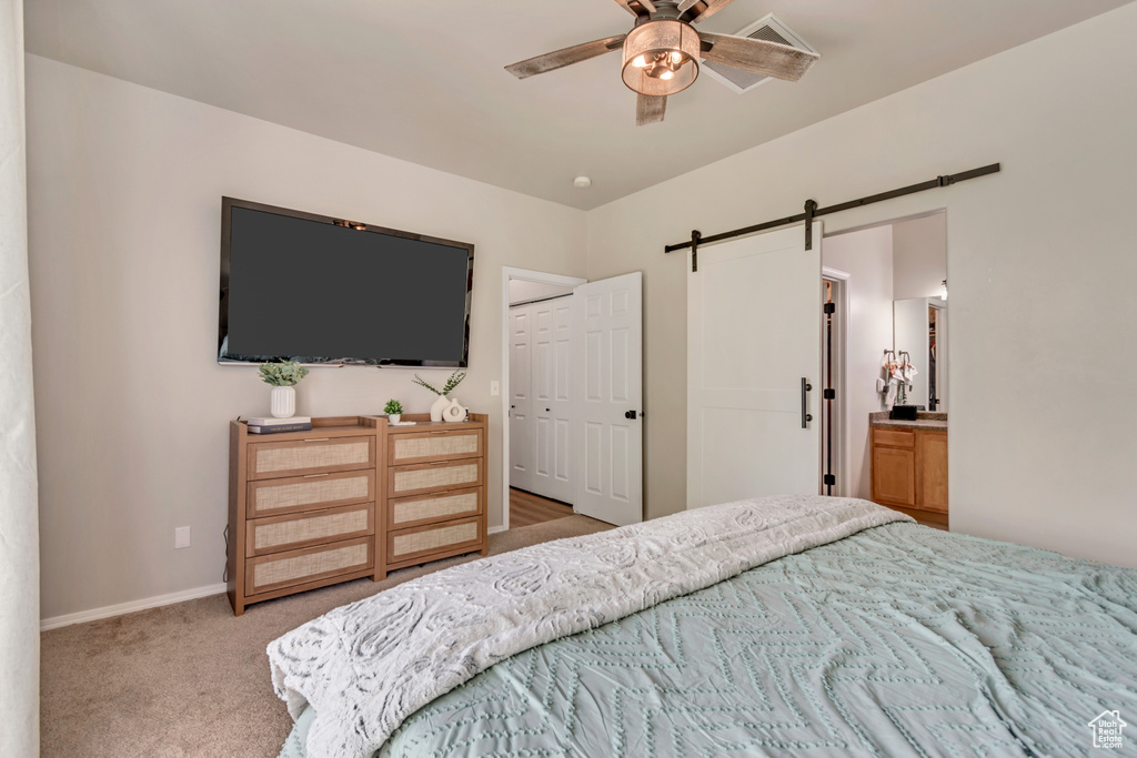 Bedroom featuring carpet floors, a closet, baseboards, a barn door, and a ceiling fan