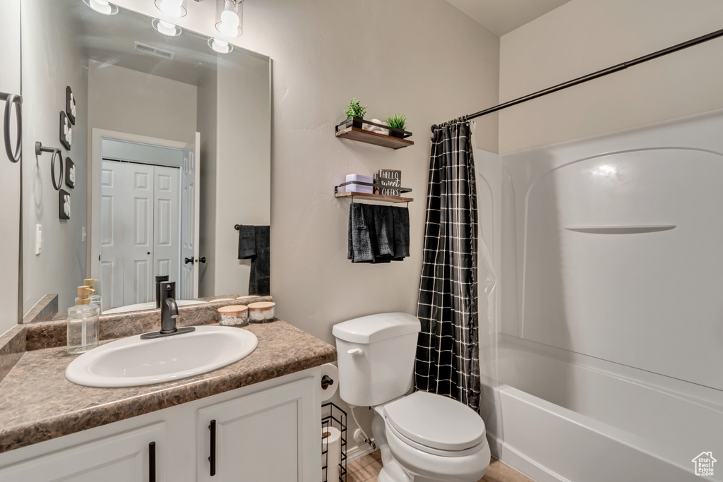 Bathroom with vanity, shower / bath combo, and toilet