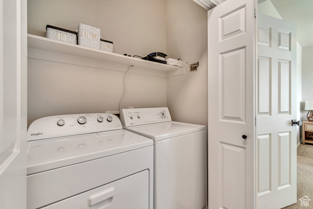 Laundry room featuring washing machine and clothes dryer, laundry area, and light colored carpet