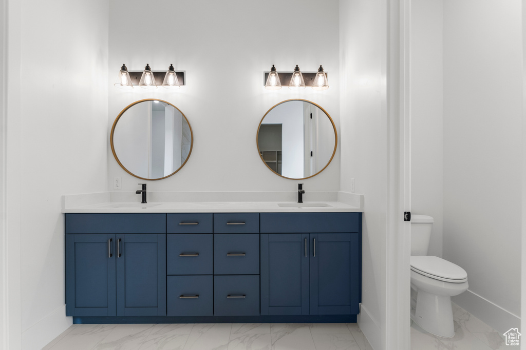 Full bath featuring a sink, toilet, and marble finish floor