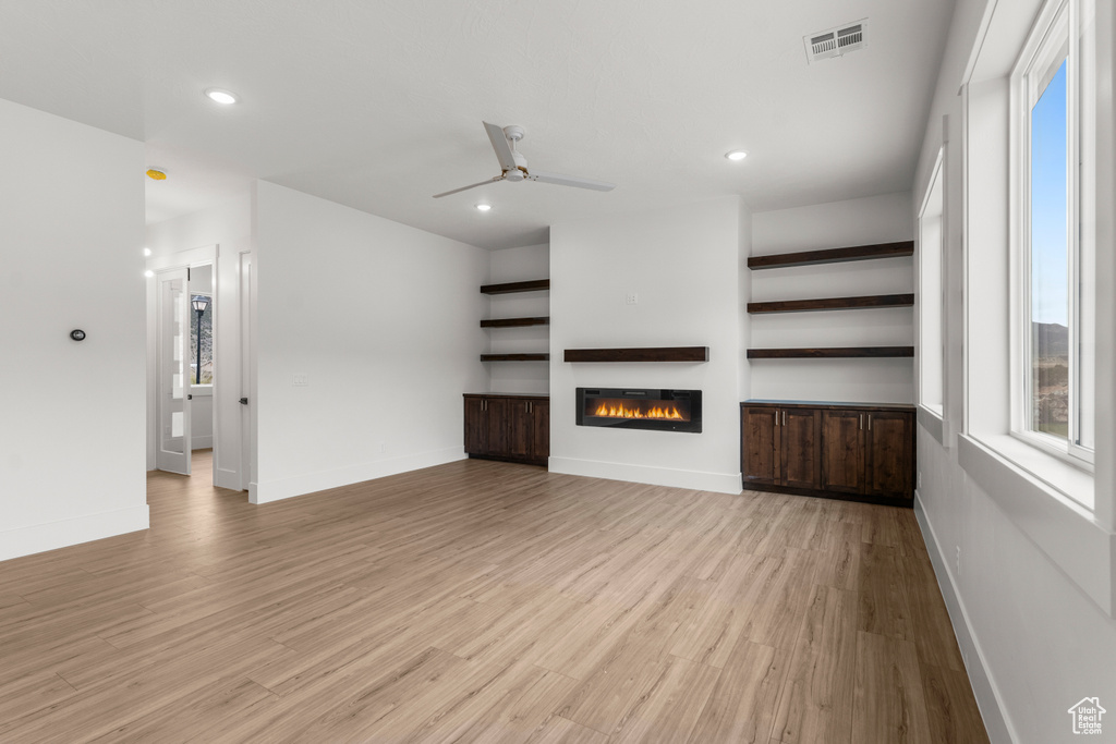 Unfurnished living room with visible vents, a glass covered fireplace, ceiling fan, recessed lighting, and light wood finished floors