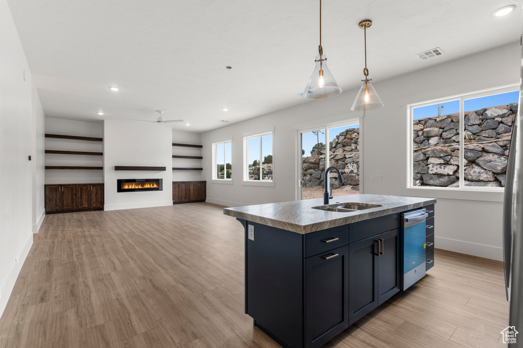Kitchen featuring visible vents, baseboards, light wood-type flooring, a sink, and dishwasher