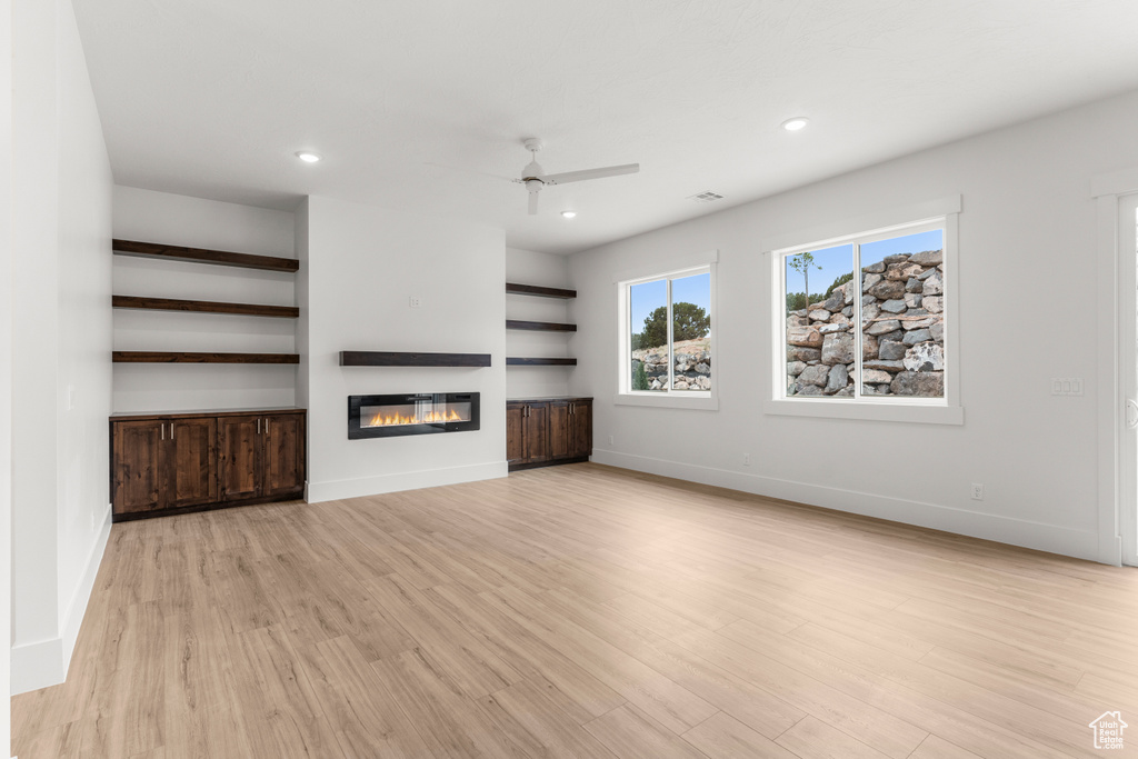 Unfurnished living room with a glass covered fireplace, baseboards, recessed lighting, a ceiling fan, and light wood finished floors