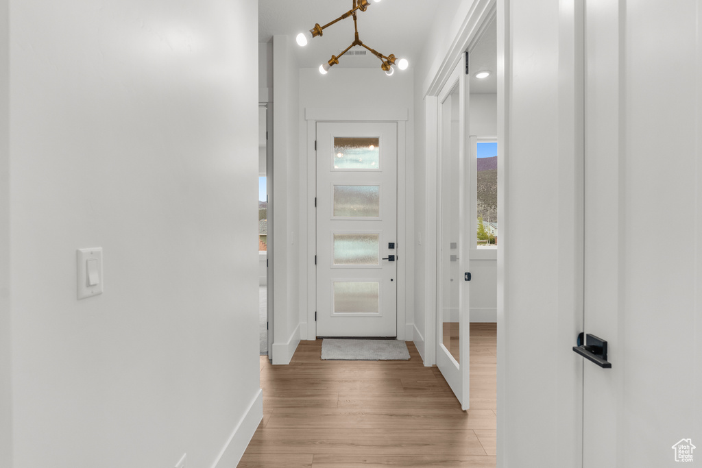 Entryway featuring baseboards, light wood finished floors, and a notable chandelier