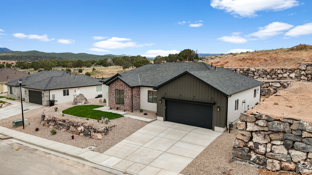 Ranch-style house with a garage, a mountain view, a shingled roof, and concrete driveway
