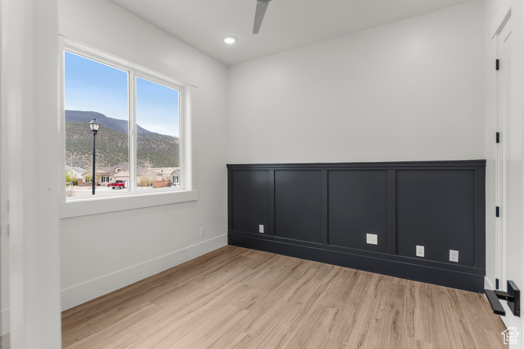Empty room featuring a ceiling fan, wood finished floors, baseboards, a mountain view, and recessed lighting