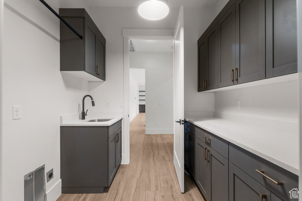 Kitchen with light countertops, baseboards, a sink, and light wood-type flooring