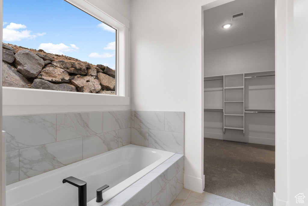 Full bath featuring visible vents, a walk in closet, and a garden tub