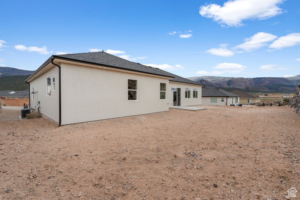 Back of property featuring central air condition unit, a mountain view, stucco siding, and a patio area
