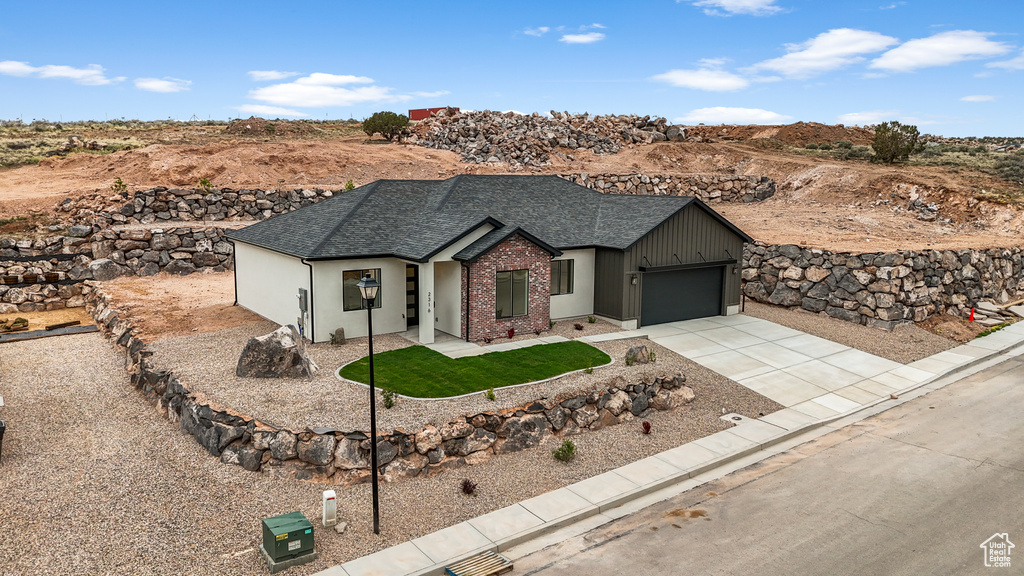 Ranch-style home featuring an attached garage, a shingled roof, a front lawn, brick siding, and concrete driveway