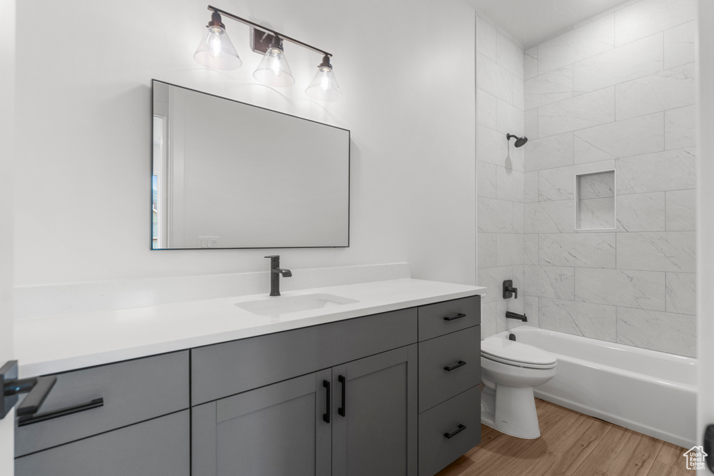 Full bath featuring vanity, shower / tub combination, wood finished floors, and toilet