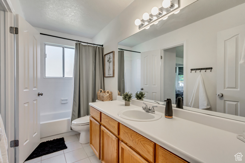 Full bathroom with tile patterned floors, vanity, toilet, and shower / bath combination with curtain