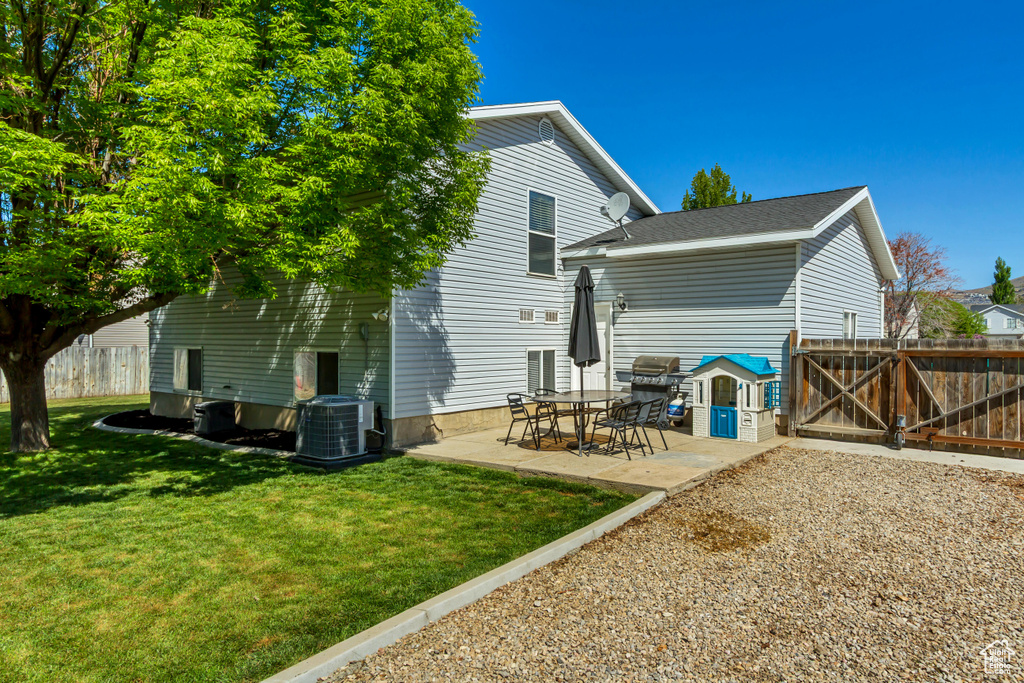 Rear view of property featuring central AC, fence, a patio, a gate, and a lawn