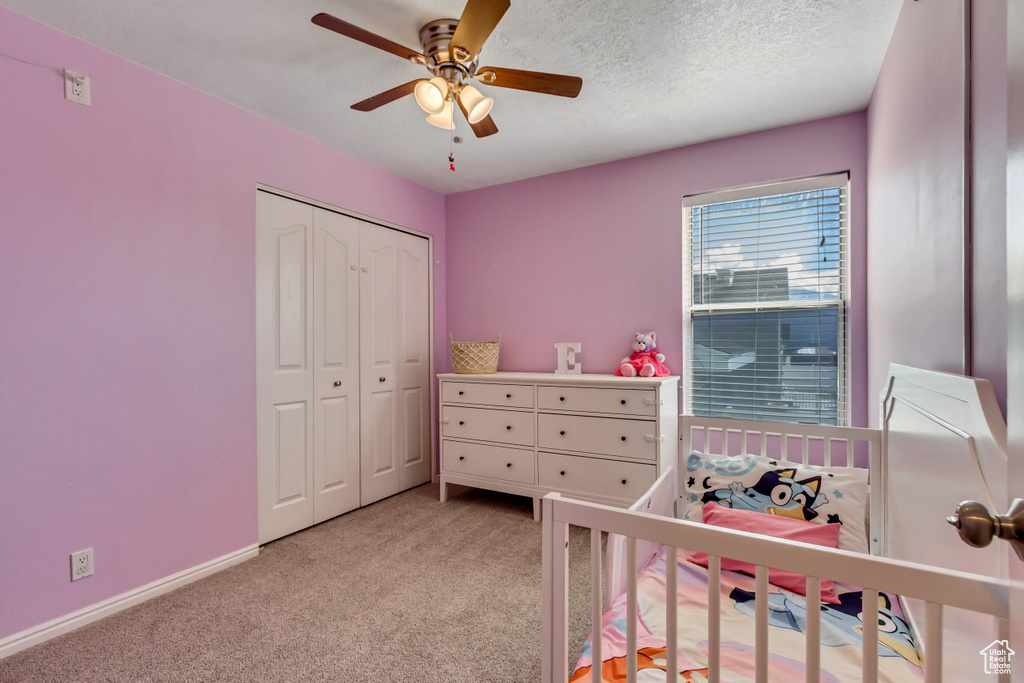 Bedroom featuring light colored carpet, a ceiling fan, baseboards, and a closet
