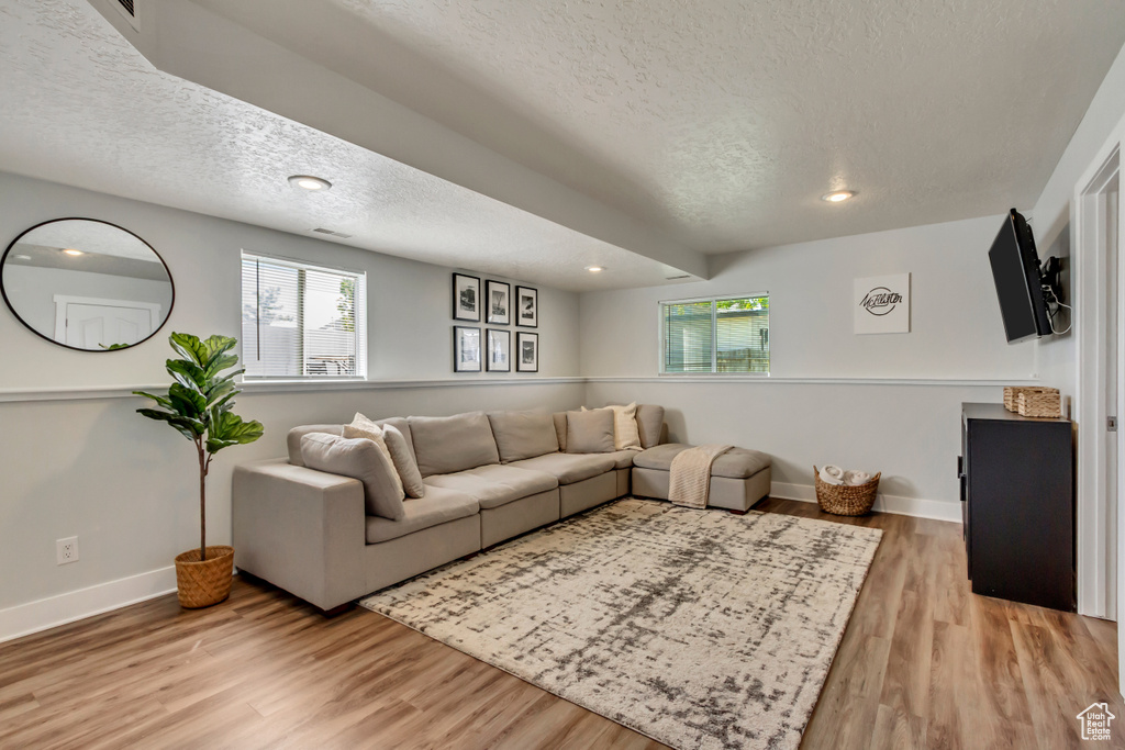 Living area featuring recessed lighting, baseboards, light wood-type flooring, and a textured ceiling