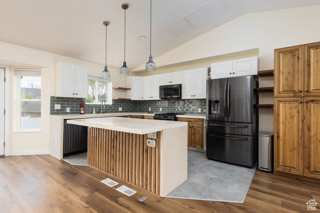 Kitchen featuring backsplash, open shelves, light countertops, refrigerator with ice dispenser, and lofted ceiling
