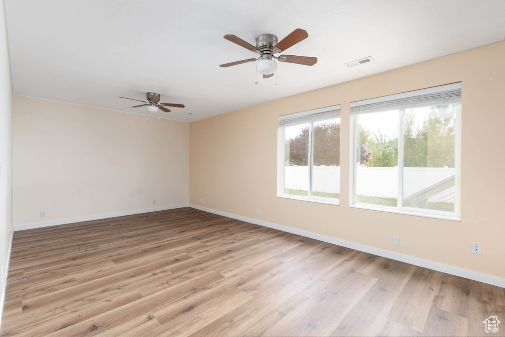 Spare room featuring baseboards, ceiling fan, wood finished floors, and visible vents