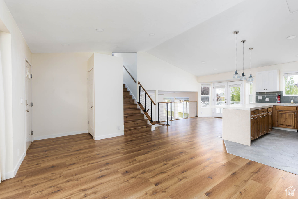 Kitchen featuring pendant lighting, light countertops, a peninsula, open floor plan, and light wood-style floors