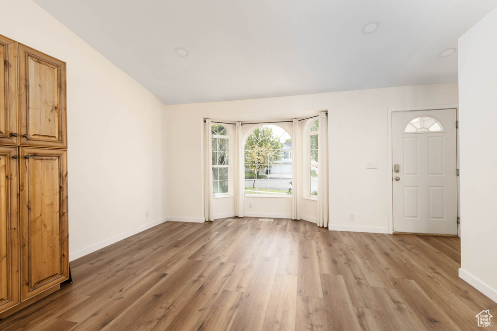 Entryway featuring light wood-style floors, baseboards, and vaulted ceiling