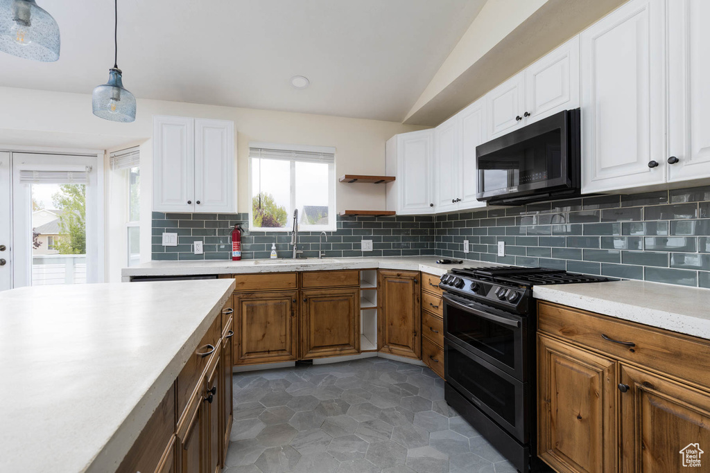 Kitchen featuring decorative backsplash, lofted ceiling, light countertops, a sink, and double oven range
