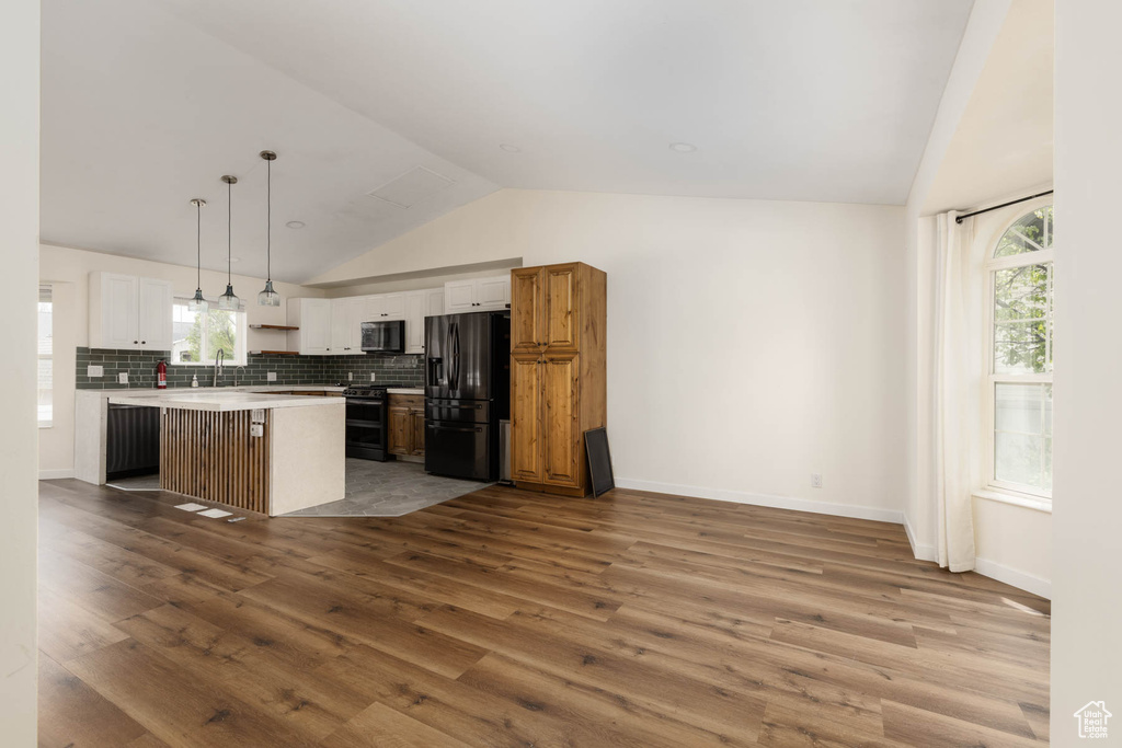 Kitchen with a center island, wood finished floors, a sink, light countertops, and black appliances