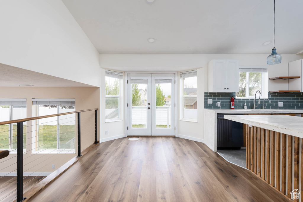 Kitchen featuring light wood-style floors, baseboards, light countertops, white cabinetry, and dishwasher