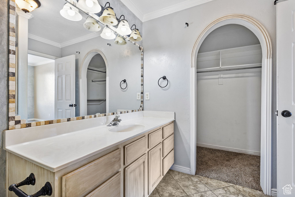 Bathroom with crown molding, baseboards, a spacious closet, and vanity