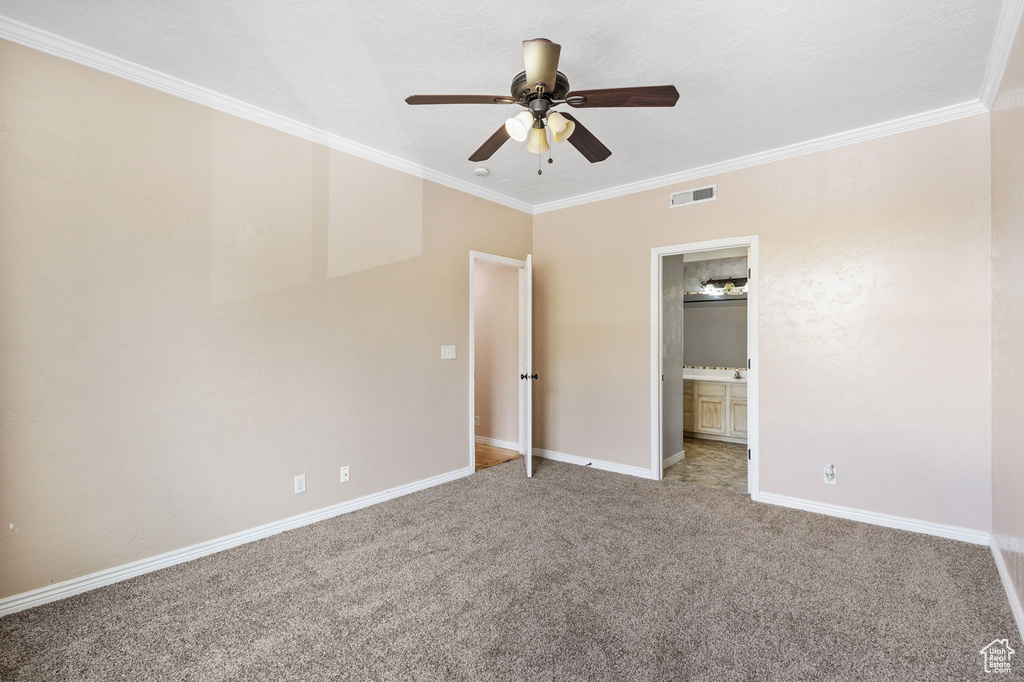 Unfurnished bedroom featuring connected bathroom, carpet, baseboards, visible vents, and ornamental molding