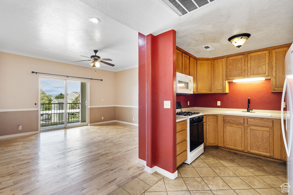 Kitchen featuring a ceiling fan, visible vents, gas range, a sink, and white microwave