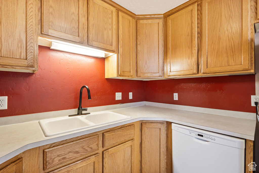Kitchen with a sink, light countertops, and dishwasher