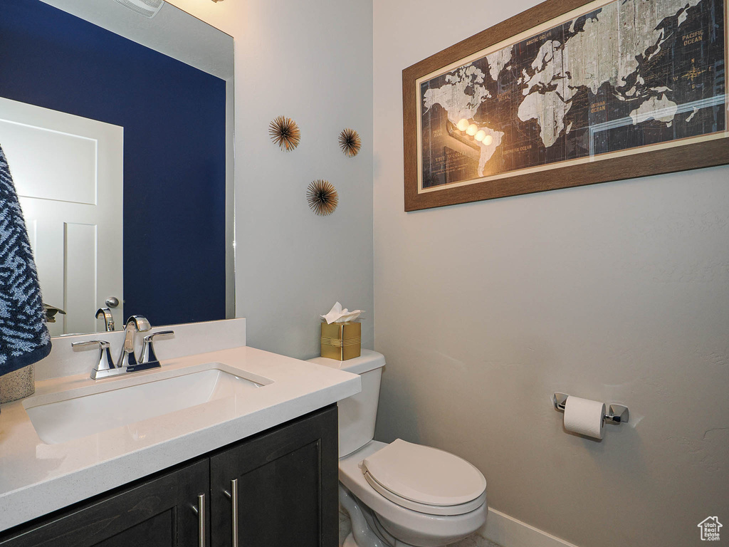 Half bath with toilet, baseboards, and vanity