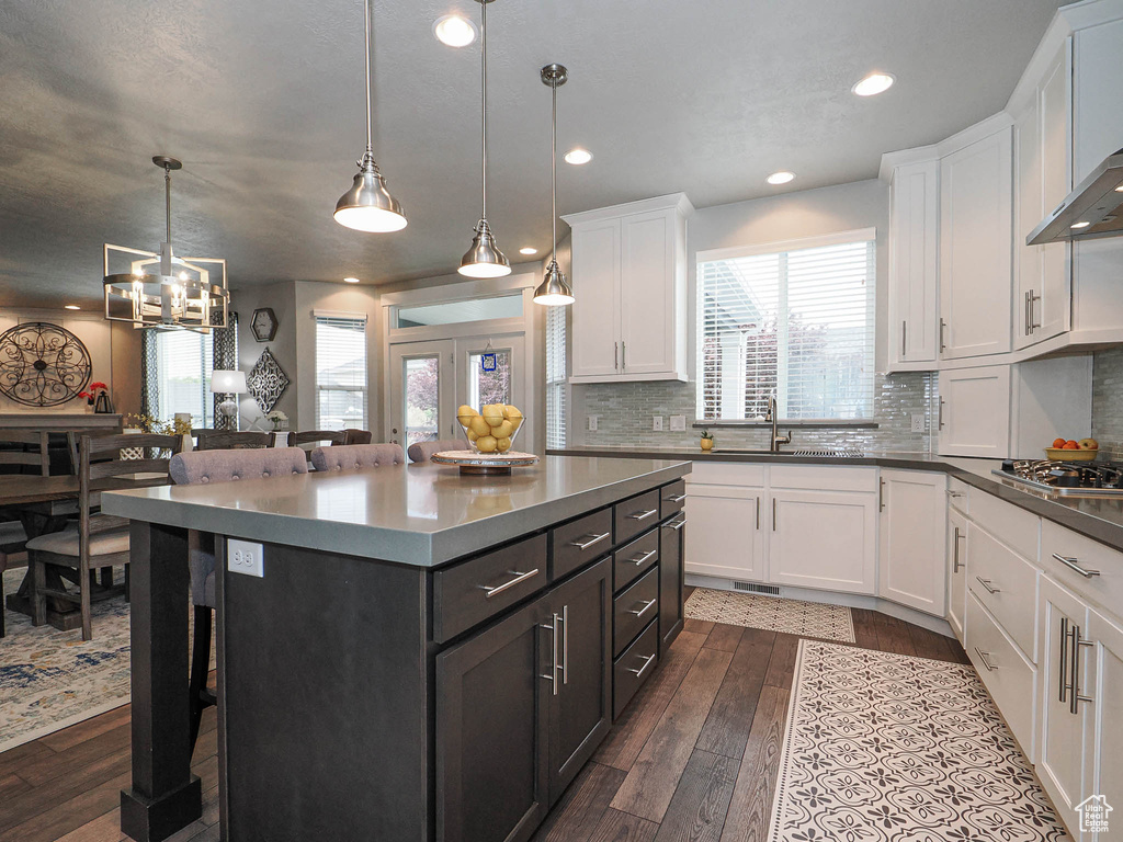 Kitchen featuring a sink, white cabinets, a kitchen bar, and dark wood-type flooring