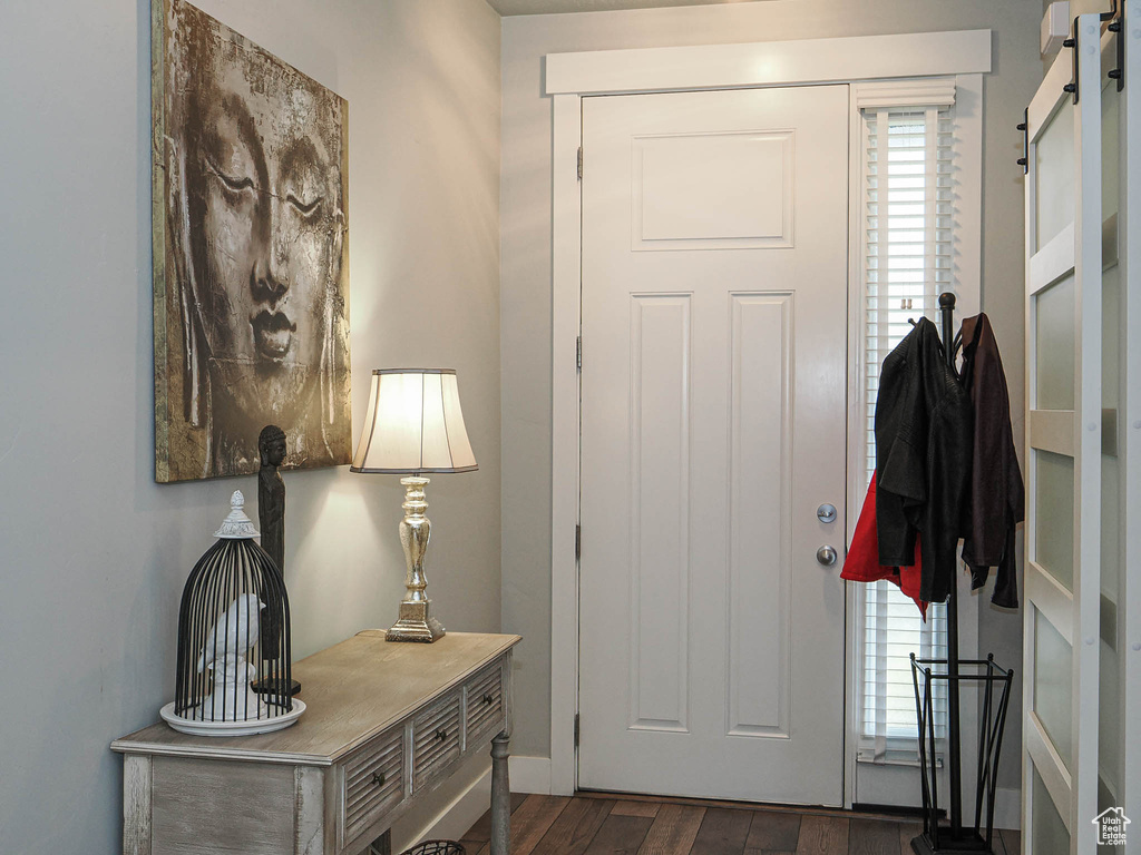 Entryway with baseboards, a barn door, and dark wood-type flooring